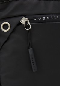 Black textured nylon bag with silver zipper and metal accents. Features logo tag and a drawstring closure for secure access.