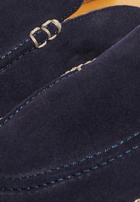 Granatowe zamszowe mokasyny z kontrastującymi niebieskimi przeszyciami i srebrnymi detalami, o gładkiej fakturze i zaokrąglonym kształcie.