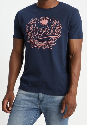 T-shirt en coton bleu marine avec un motif graphique rose, texte "Esprit" et un motif de laurier. Manches courtes et col rond.