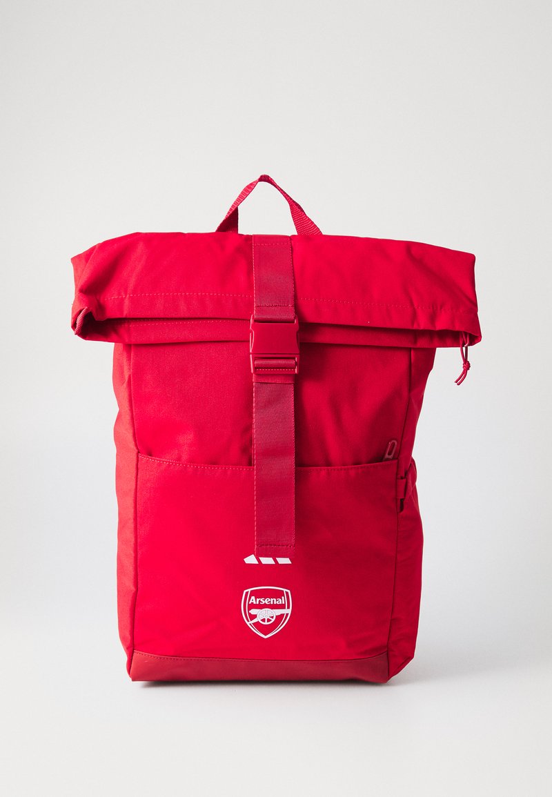 Red backpack with a roll-top design, adjustable strap, front pocket, and logo. Made of smooth, durable fabric with a matte finish.