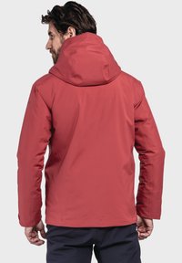 Rote wasserdichte Jacke mit Kapuze, mit einer glatten Oberfläche und einem schlanken Design. Verstellbare Manschetten und ein dezentes Logodetail sind sichtbar.