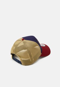 Kappe in Rot, Blau und Beige. Verfügt über ein Netzrücken, einen flachen Schirm und einen kleinen roten Knopf oben. Logostickerei innen sichtbar.