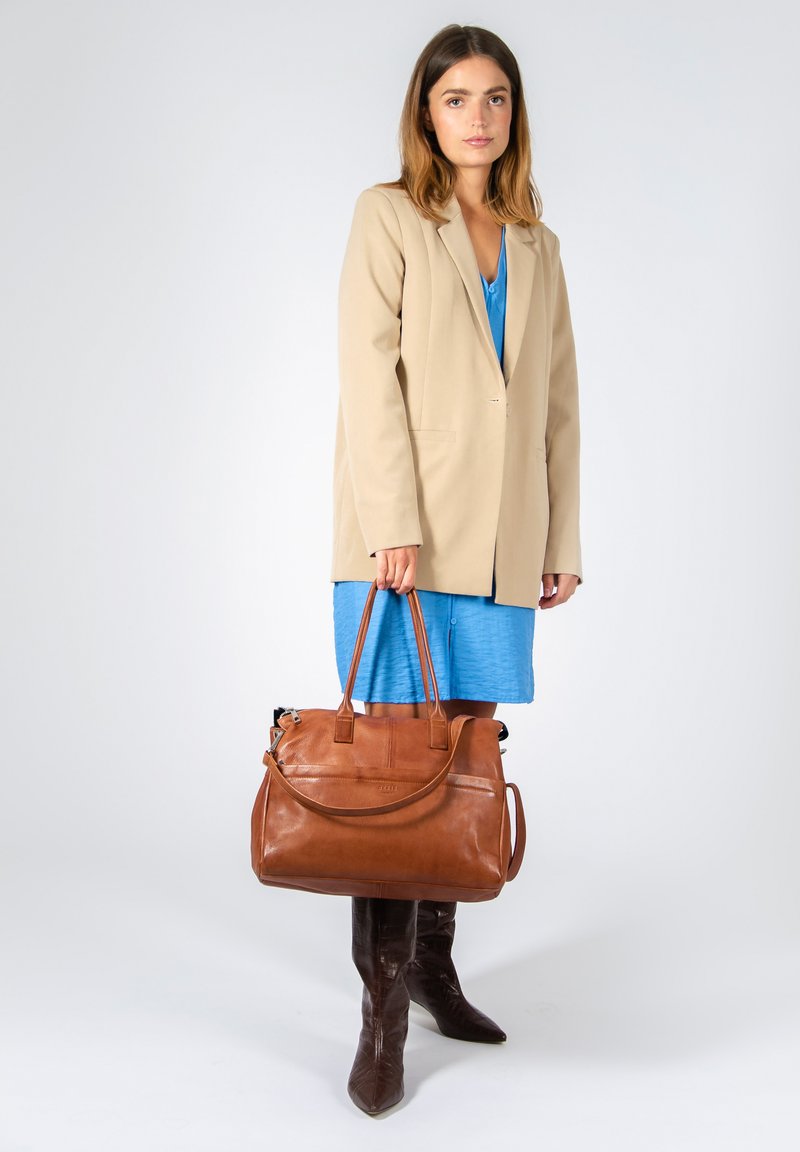 Sac à main en cuir marron avec deux poignées et une bandoulière réglable ; texture lisse, forme rectangulaire et détails de couture subtils.