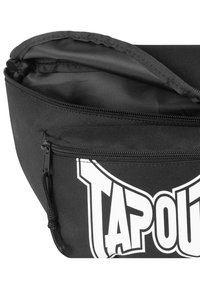 Borsa nera realizzata in tessuto resistente, con una cerniera superiore e una tasca frontale. Logo bianco ben visibile stampato sulla parte anteriore. Texture liscia.