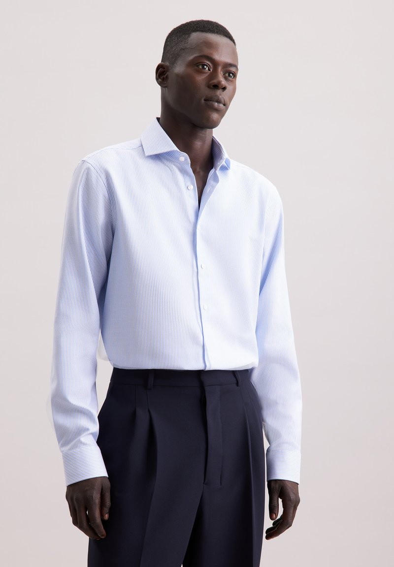 Lichtblauw gestreept overhemd met lange mouwen en een button-down kraag, gecombineerd met donkere, op maat gemaakte broeken, met subtiele textuurdetails.