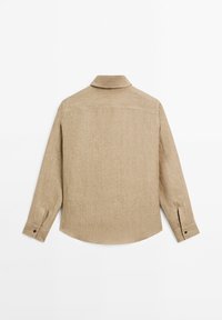 Beige langærmet skjorte med knapolar, vist fra bagsiden, med en lige krave og enkle sømdetaljer.