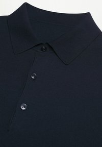 Polo en bleu marine avec une texture côtelée, doté d'un col classique et d'une patte de boutonnage à trois boutons. Design simple sans motifs ni accents.