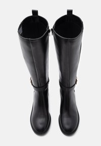 Botas de couro pretas até ao joelho com uma textura suave, ponta arredondada, fechos de correr laterais e detalhes em ouro decorativos próximos ao tornozelo.