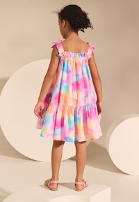 Vestido colorido sin mangas con un diseño de capas. Hecho de una tela ligera que presenta una mezcla de tonos rosa, azul y naranja. Tirantes con volantes.