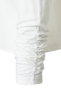 Long-sleeve white top with gathered texture at the cuffs. Made from soft fabric, featuring a smooth finish and subtle stitching detail.