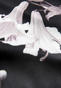 Material floral cu crini albi mari pe un fundal negru, textură netedă și detalii intricate în petalele și tulpinile florilor.