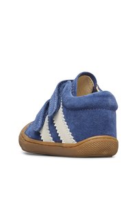 Modrá semišová bota se bílými zigzagovými akcenty, suchým zipem, zaobleným tvarem, béžovou gumovou podrážkou a strukturovaným detailem na spodní straně.