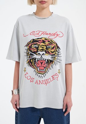 Gray oversized t-shirt featuring a colorful tiger graphic, red and gold accents, and the text "Ed Hardy Los Angeles" in bold lettering.