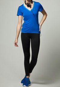 Blue v-neck active t-shirt, black leggings, and blue athletic shoes. Equipped with black headphones, featuring a fitted design and smooth texture.