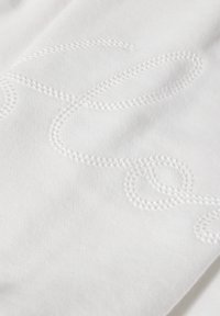 Tessuto bianco con delicate ricami bianchi in un motivo a spirale. Texture morbida, finitura liscia, senza hardware o dettagli visibili.