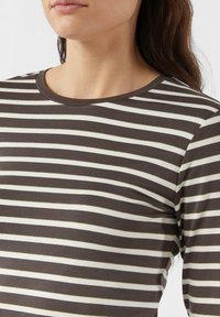 Brązowo-kremowa bluzka w paski z długim rękawem i okrągłym dekoltem. Miękki materiał o gładkiej fakturze. Paski biegną poziomo przez całą odzież.