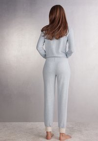 Lichtblauw pyjama set gemaakt van zachte stof, met een langemouwen top en broek met elastische tailleband en crèmekleurige boorden.