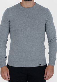 Szary dzianinowy sweter z okrągłym dekoltem, długimi rękawami oraz ściągaczami na mankietach i u dołu. Zawiera małą metkę z logo na dolnym boku.