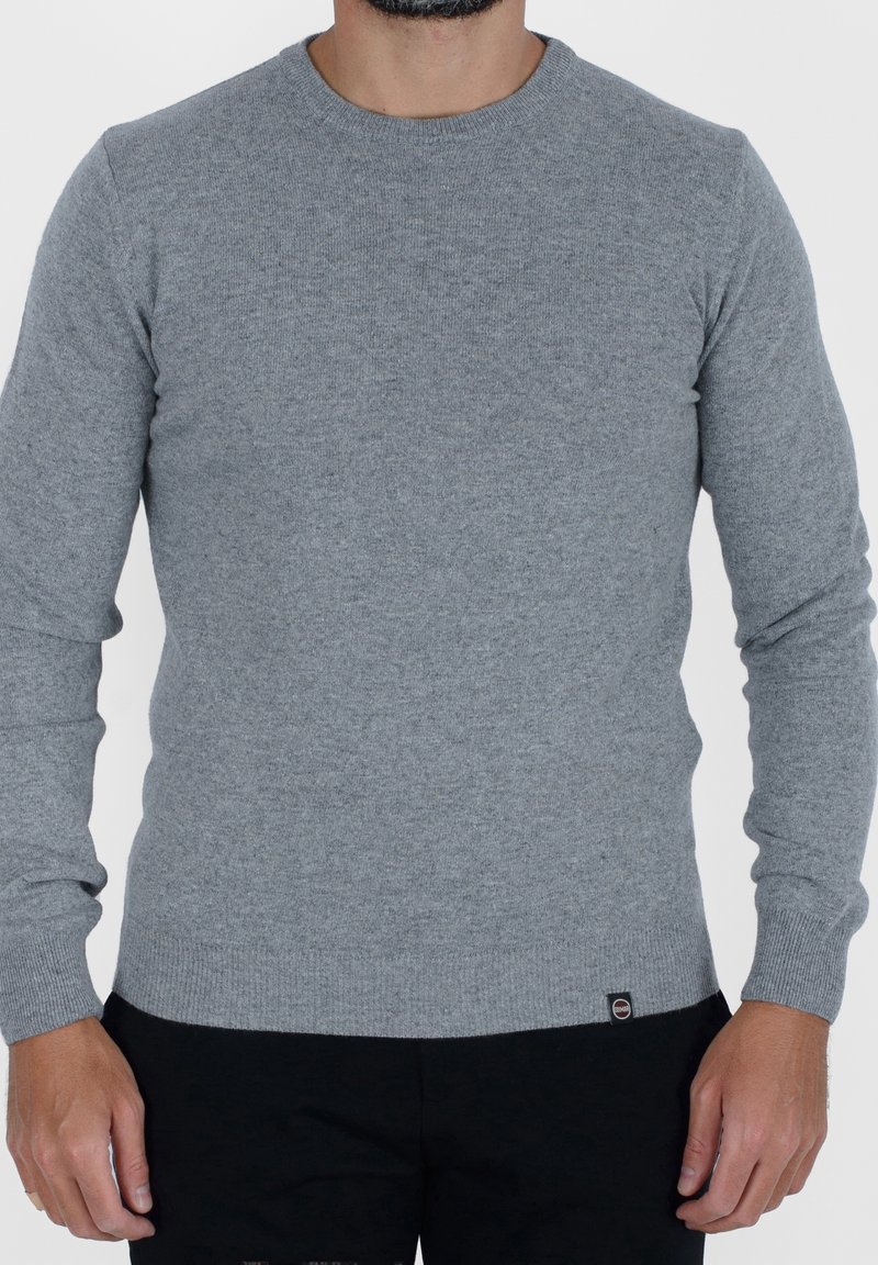 Szary dzianinowy sweter z okrągłym dekoltem, długimi rękawami oraz ściągaczami na mankietach i u dołu. Zawiera małą metkę z logo na dolnym boku.