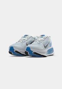Baskets de course bleu et blanc avec un dessus en maille, un grand swoosh gris et une semelle texturée. Comprend une semelle intermédiaire rembourrée et un système de laçage.