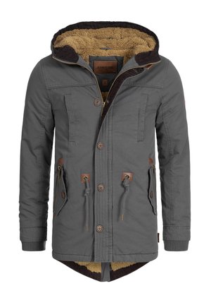 Veste grise avec capuche, dotée d'une doublure en fourrure brun, de boutons en bois et de plusieurs poches avant. Comprend un cordon de serrage et des poignets côtelés.
