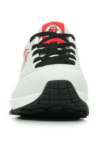 Sneaker bianca con lacci neri e un accento rosso sulla linguetta. Presenta una suola in gomma con un battistrada testurizzato per una migliore aderenza. Logo dei Rolling Stones visibile.