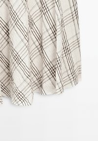 Tissu de couleur claire, à texture froissée, avec un motif à carreaux en lignes brunes et noires, présentant un design fluide et un ourlet s'évasant légèrement.