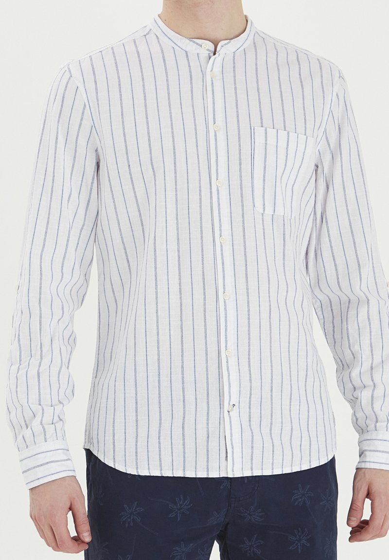 Camisa de algodón de botones en blanco con rayas verticales azules. Presenta un cuello mao y un bolsillo en el pecho. Mangas largas con puños abotonados.