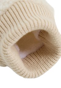 Poignet beige tricoté avec texture côtelée ; doublure intérieure douce et duveteuse. L'ouverture révèle une finition lisse, mettant en avant la chaleur et le confort.