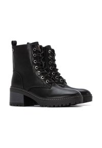 Botas de tobillo de cuero negro con un diseño de cordones, ojales plateados y un tacón texturizado. Cuentan con una lengüeta para tirar y una suela resistente.