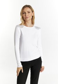 Witte lange mouw trui met een ronde halslijn en textuurelementen op de schouders; gladde stof en getailleerd ontwerp.