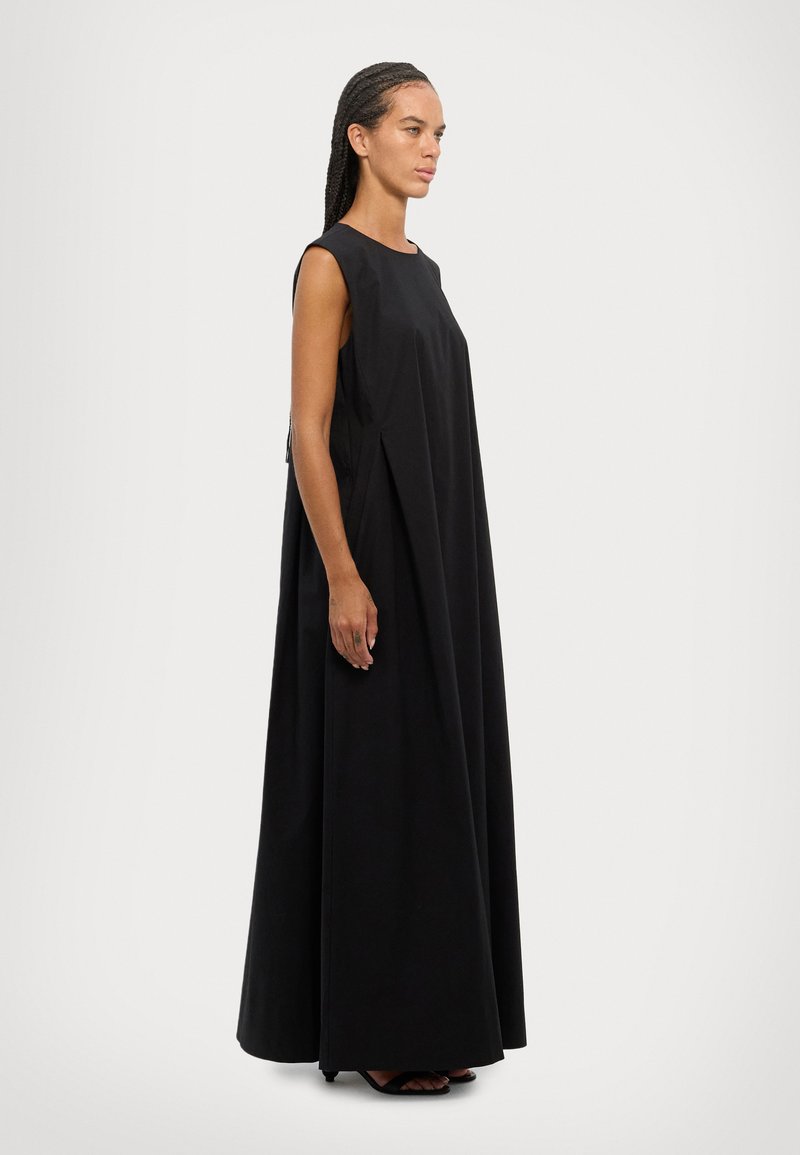 Black sleeveless maxi dress with a loose fit, crafted from smooth fabric. Features side pleats and a subtle side zipper detail.
