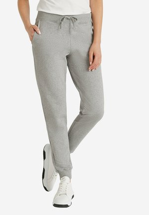 Grijze katoenen joggers met een trekkoord in de taille, twee zijzakken en taps toelopende boorden, gecombineerd met witte sportschoenen.