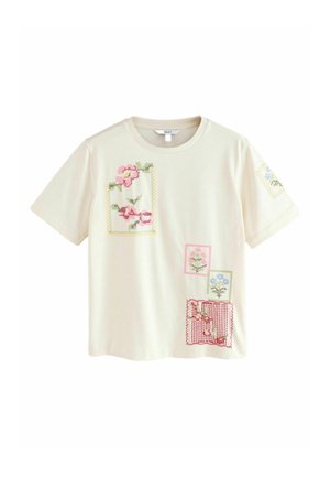 Kreamfärgad bomulls t-shirt med färgglada broderade blommotiver. Korta ärmar och rund halsringning. Avslappnad passform med varierade mönster.