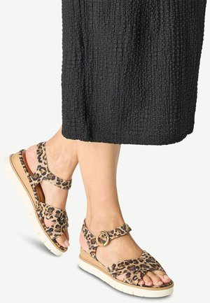 Leopard print wedge sandals with a tan base, featuring a buckle ankle strap and white outsole for contrast. Textured, soft footbed visible.