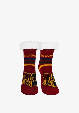 Rote Socken mit weißen, flauschigen Bündchen, die das Hogwarts-Wappen und einen Schriftzug zeigen, und darüber grüne, gelbe und blaue Streifen oberhalb des Knöchels.