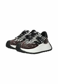 Schwarz-weiße Sneaker mit einer strukturierten Oberseite im Zebramuster, verziert mit silbernen Nieten und einer dicken weißen Sohle.