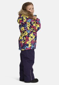 Färgglad vinterjacka med blommönster, huva med fuskpäls, tillsammans med lila byxor. Har inskuren midja och elastiska ärmslut.