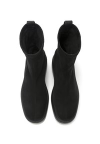 Botines negros hechos de suave ante con una textura lisa. Presentan una punta redondeada y un diseño minimalista. Incluyen tiradores para facilitar su puesta.