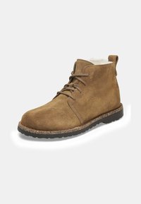 Stivali ankle in suede marrone con design lacciato, suola in gomma e imbottitura interna morbida. Presenta un'etichetta sul retro per facilitarne l'indossamento.