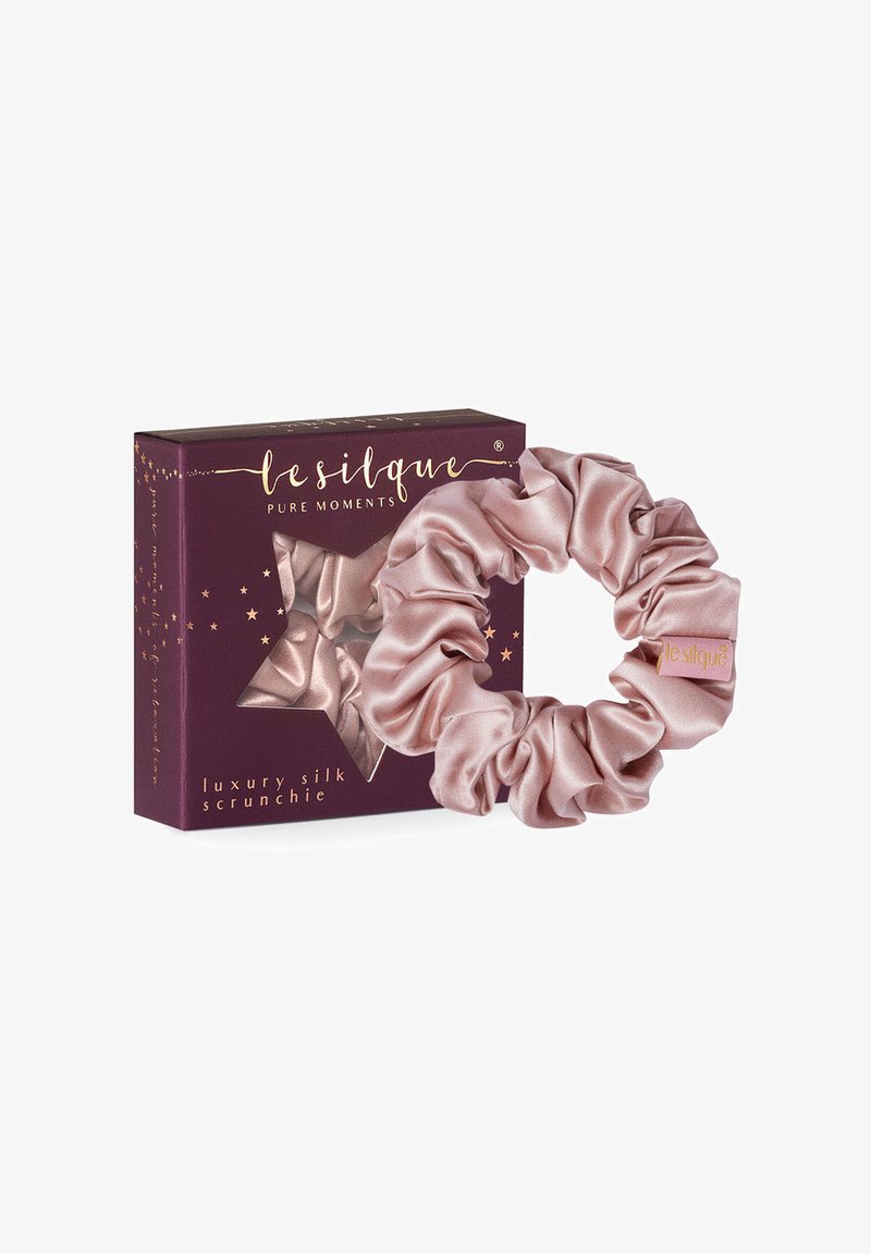 Luxuriöse Seidenscrunchie in sanftem Rosa, mit einer glatten Textur und vollem, gerafftem Design. Verpackt in einer dunkellila Box mit goldenen Akzenten.