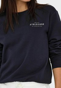 Marinblå sweatshirt med rund hals, ribbede manchetter og nederste kant. Har hvid tekst "ONLY PLAY ATHLEISURE EST. ACTIVE LIFE 2006."
