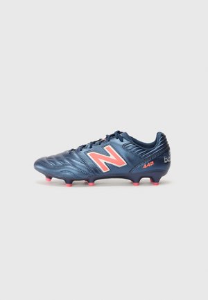 Blue synthetic soccer cleat with serrated texture, featuring a large orange "N" logo, pink accents, and conical studs for traction.