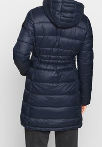 Mörkblå puffad parka med huva, med horisontell quiltad design, elastisk midja och slät textur. Inkluderar svarta accentdetaljer.