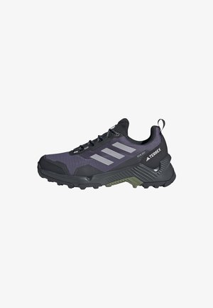 Scarpa da esterno nera e viola con tomaia in rete, punta rinforzata, strisce grigie e suola in gomma con lugs di trazione per stabilità.