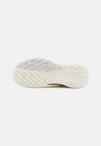 Suela de zapato con una superficie de goma texturizada; presenta una mezcla de colores gris y crema, patrones geométricos y un relieve prominente para mayor agarre.