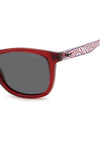 Lunettes de soleil en plastique rouge avec une forme élégante et des verres gris. Les branches affichent un motif abstrait bleu et blanc, arborant la marque "Polaroid."