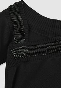 Pull noir avec un col côtelé et des embellissements décoratifs en perles noires le long des épaules. Texture douce et design ajusté.