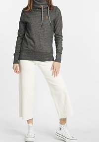 Grå bomullsblandning sweatshirt med snörning och svarta och vita dragsnören, kombinerad med vita vida byxor och vita sneakers.