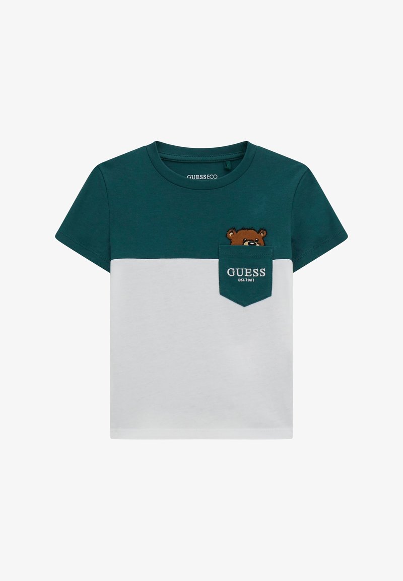Roheline ja valge lühikeste varrukatega T-särk, millel on ees tasku, koos karu graafika ja "GUESS" tekstiga, mis on tikkitud taskusse. Puuvillane materjal.